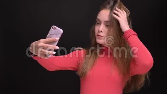 年轻美丽的白种人女性在手机上自拍的特写照片她在手机前甩着头发摆姿势视频的预览图