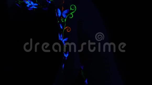 一个在俱乐部跳舞的年轻女子身上的紫外线身体艺术蝴蝶视频的预览图