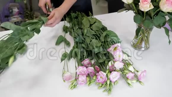女花艺师工作时桌上放着白色和紫色的花双手特写视频的预览图