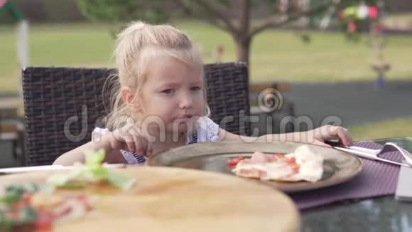 在夏天的咖啡馆里一个小女孩在吃披萨视频的预览图