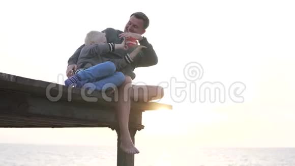 爸爸和儿子一起看大海里的日落视频的预览图