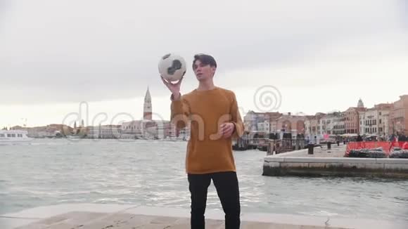 一个人在海边的看台上踢足球把球旋在他的手指上视频的预览图