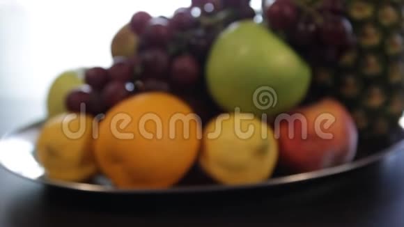 镜头从模糊幻灯片在一个盘子与水果菠萝苹果红葡萄柠檬橘子视频的预览图