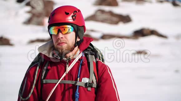 白种人的年轻登山者留着胡子站在雪坡上环顾四周戴着眼镜视频的预览图