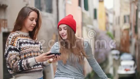 意大利威尼斯两个年轻的女人站在小桥上在一条水道的背景上自拍视频的预览图