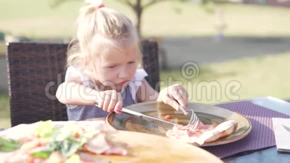 在夏天的咖啡馆里一个小女孩在吃披萨视频的预览图