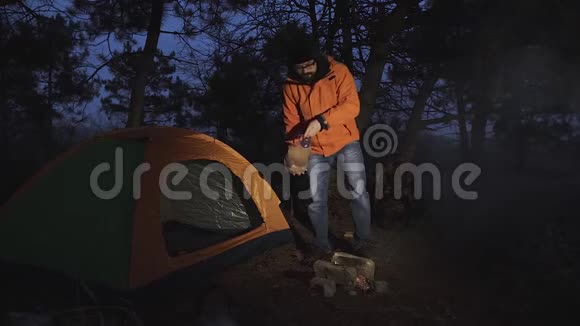 一个游客把水倒在他点燃的火上然后进入他的帐篷里过夜视频的预览图