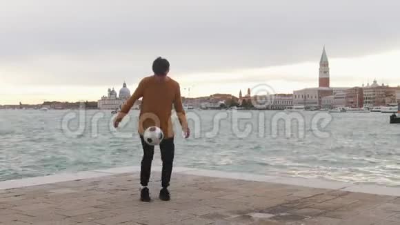一个人在海边的看台上踢足球用腿踢球视频的预览图