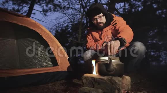在夜林中帐篷附近的一名游客引发了火灾一个水壶被放在火的上方他把那个人视频的预览图