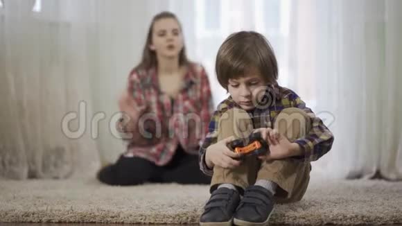 姐姐骂弟弟弟弟正在玩玩具车坐在地上的毛茸茸的地毯上视频的预览图