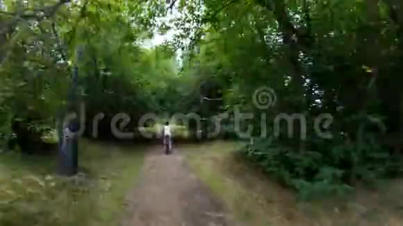 在公园里骑自行车女孩骑自行车在森林小径上很快时间流逝视频的预览图