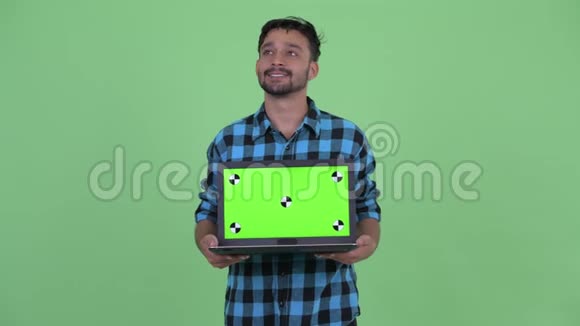 快乐的留着胡须的波斯时髦男人一边看着笔记本电脑一边思考视频的预览图