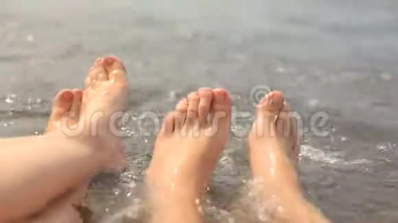 女人和男人脚在鹅卵石海滩上的海里休息和旅行度假视频的预览图