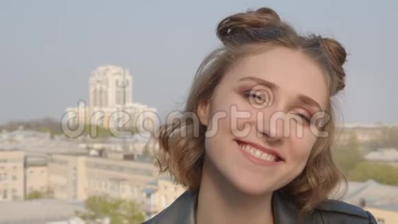 年轻漂亮的高加索女性留着发髻在镜头前的特写镜头背景是城市景观视频的预览图