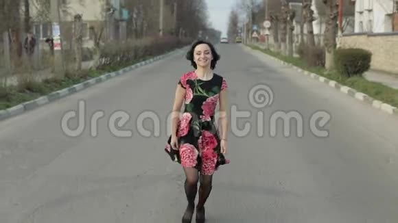 漂亮的年轻女子穿着一件连衣裙花在公路上奔跑视频的预览图