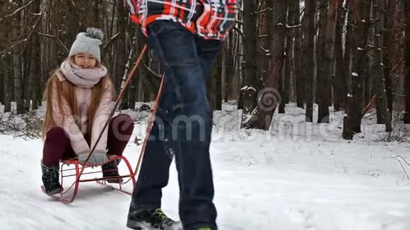 少女喜欢坐雪橇男孩拉着雪橇慢动作视频的预览图