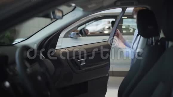 年轻漂亮的女士穿着蓝色西装打开车门坐在前面的乘客座位上现代女孩视频的预览图