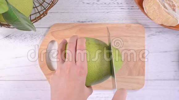 一位年轻的亚洲妇女正在家里的厨房里切新鲜的柚子厨房在明亮的白色木桌和砧板上俯视图视频的预览图