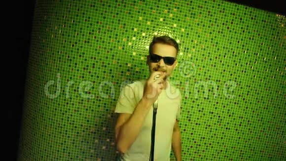 一个黑发男人戴着太阳镜拿着麦克风在镜头前来回移动视频的预览图