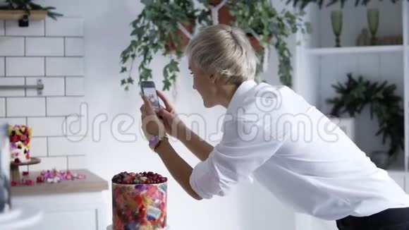 糖果博客穿着白色衬衫的女人在用鲜花装饰蛋糕糖果师装饰蛋糕视频的预览图