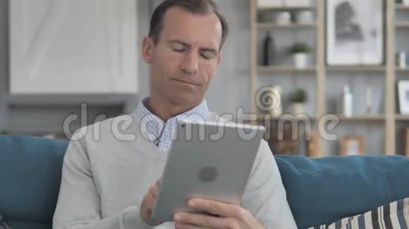 中老年人在沙发上放松时使用平板电脑视频的预览图