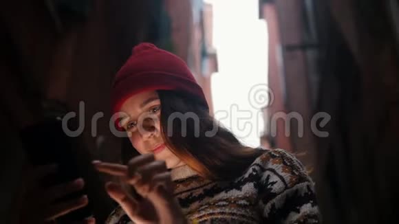 一个年轻的女人站在街上看着手机屏幕一道光照亮了她的脸视频的预览图
