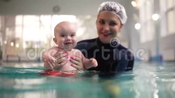 可爱快乐的小宝宝正在游泳池里的水下游泳直到妈妈帮他弄到视频的预览图