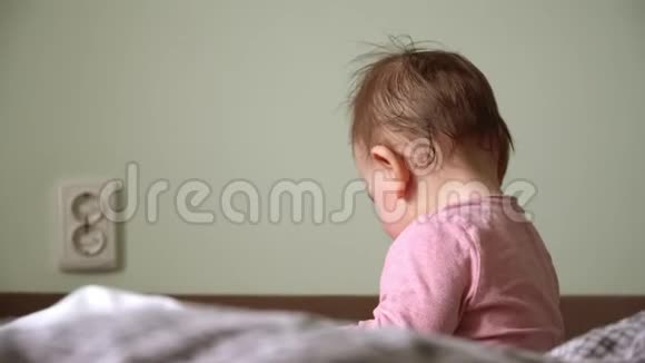 一个大眼睛躺在床上看着摄像机的微笑小女孩视频的预览图