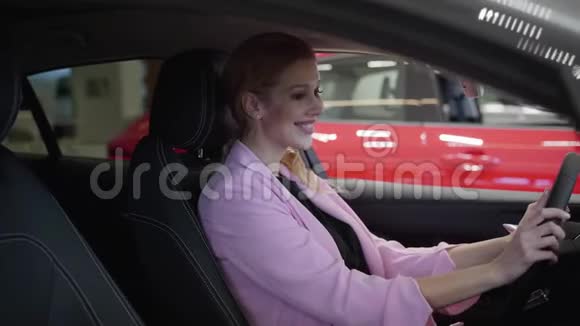 自信微笑的女人穿着粉红色的夹克坐在车里看着后视镜近距离现代女性选择视频的预览图