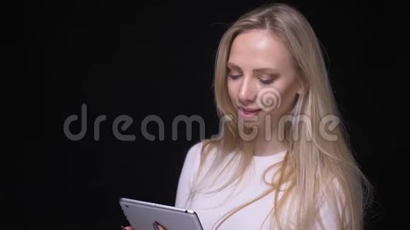 使用平板电脑拍摄年轻漂亮金发女性的特写肖像并显示绿色屏幕用相机观看摄像机视频的预览图