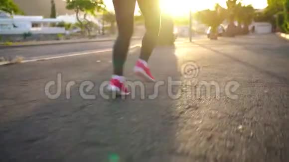 日落时分女人的腿沿着街道在棕榈树之间奔跑后景健康的生活方式视频的预览图