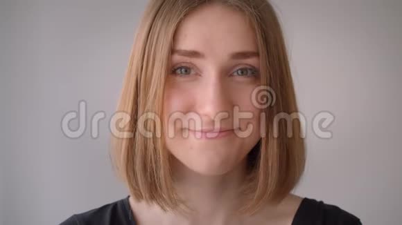 一幅年轻可爱的白种人女孩的特写照片她微笑着看着空荡荡的房间里的摄像机视频的预览图