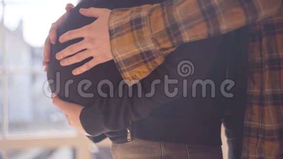 侧面看幸福的不可辨认的十几岁夫妇在家里在一起那个年轻人抚摸着他怀孕的肚子视频的预览图