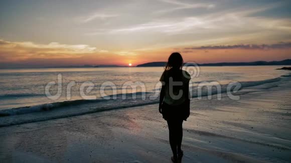 日落时分一位年轻女子在热带海滩上缓慢地走进大海视频的预览图