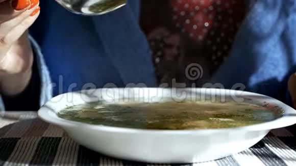 女人的手在鸡面汤里拿着勺子传统鸡汤放在碗里视频的预览图