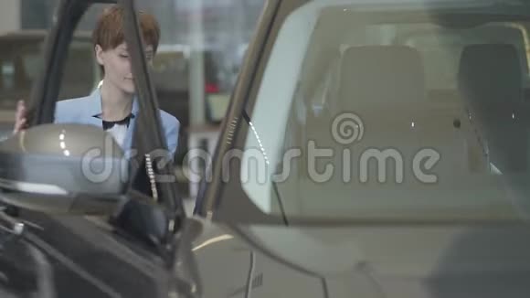 年轻漂亮的女士穿着蓝色西装打开车门坐在里面的汽车表演现代女孩选择视频的预览图