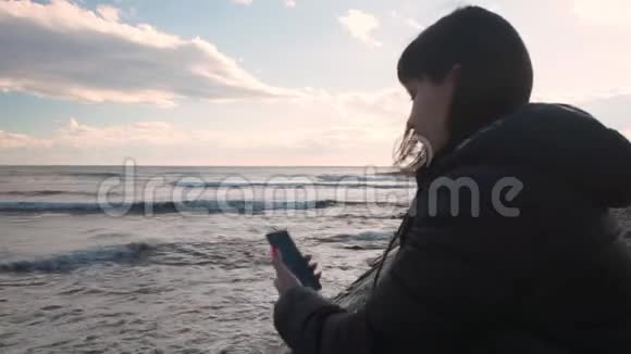 年轻女孩坐在沙滩上在电话里脱了身视频的预览图