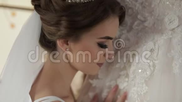 美丽可爱的新娘穿着睡衣站在婚纱附近看着相机特写镜头婚礼早视频的预览图