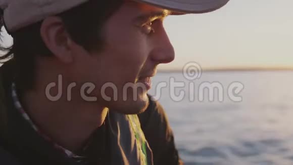 迷人的人戴着帽子在美丽的日落时在海上放松男子乘船度假自然旅游视频的预览图