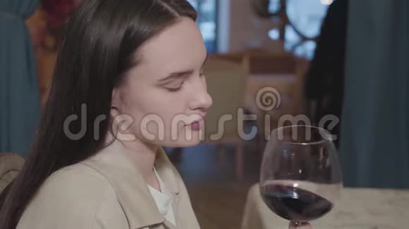特写肖像美丽的年轻女孩在餐馆喝红酒可爱的女人享受晚餐和放松视频的预览图