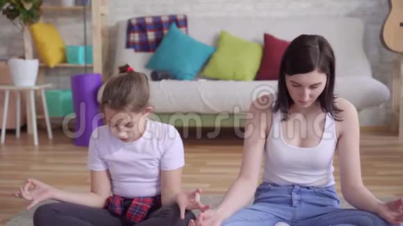 把坐在地板上做瑜伽的母亲和女儿关起来视频的预览图