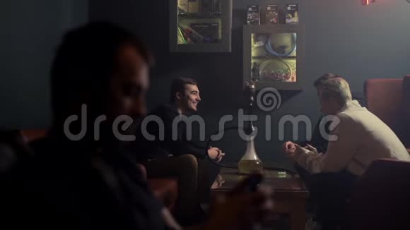 三个快乐的年轻朋友无忧无虑地抽烟慢动作地在钩子上聊天视频的预览图