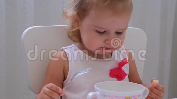 婴儿女孩在白色背景的小儿童桌上吃婴儿食品儿童的营养和喂养视频的预览图