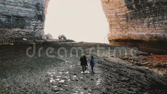 在诺曼底史诗般的巨大拱门下Drone跟随着快乐的游客夫妇沿着令人难以置信的阿拉巴斯特低潮海滩散步视频的预览图