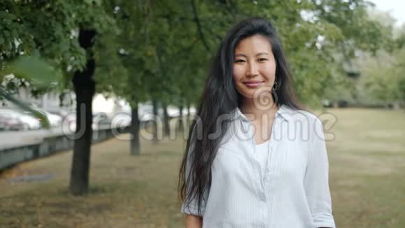 夏天在城市公园里美丽的亚洲女士在镜头前微笑的慢动作视频的预览图