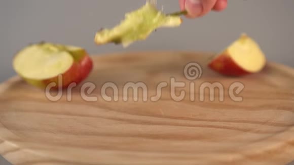 一只手用苹果片把苹果芯放在木表面视频的预览图