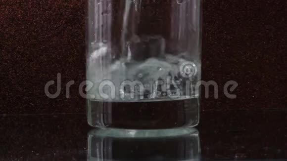 玻璃透明玻璃中的冰块和倒入黑色背景的水视频的预览图