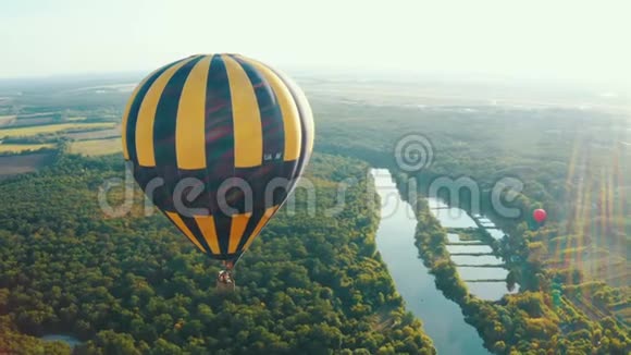蓝色天空中的黄色热气球气球飞过树木美丽浪漫夏日视频的预览图