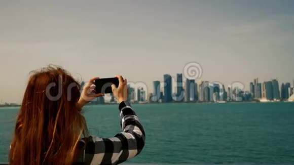 多哈卡塔尔的女孩用智能手机拍照到摩天大楼视频的预览图