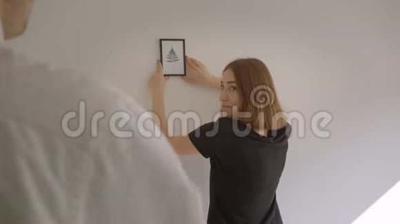 年轻幸福夫妇搬进一间舒适的公寓的特写肖像女人拿着一张照片决定视频的预览图